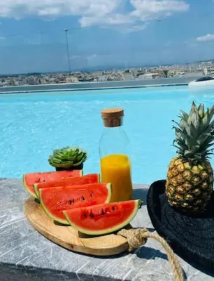 a plate of watermelon and a bottle of juice and a plate of pineapple at Kallitheas Maison with Shared Pool in Athens