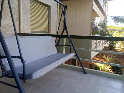 a swing on a balcony in front of a window at 2BD apartment with large balcony near the sea!! in Athens