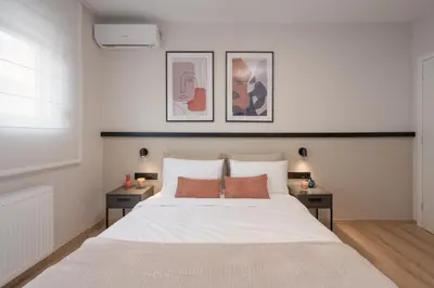 a bedroom with a large white bed with two tables at Upscale Apartment in Chalandri with Large Terrace in Athens
