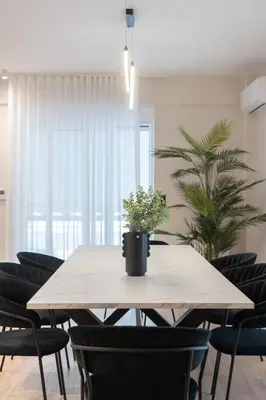 a dining room table with chairs and a potted plant at Upscale Apartment in Chalandri with Large Terrace in Athens