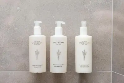 a trio of three shampoo bottles sitting on a bathroom floor at Evia Hotel in Athens