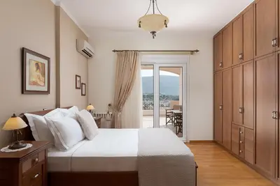 a bedroom with a white bed and a balcony at Ema's Guest House in Porto Rafti