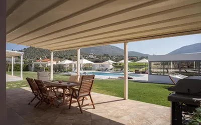 a patio with a table and chairs and a pool at Ema's Guest House in Porto Rafti