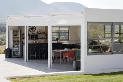 a white house with a kitchen and a table at Ema's Guest House in Porto Rafti
