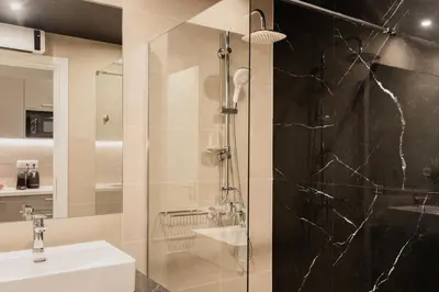 a bathroom with a glass shower and a sink at WYZ Museum by UPSTREET in Athens