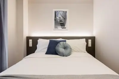 a bed with a blue pillow on top of it at WYZ Museum by UPSTREET in Athens