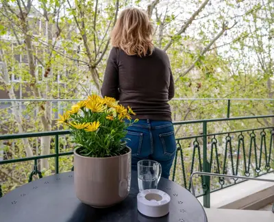a woman standing on a balcony with a vase of yellow flowers at Mia Homes - Acropolis in Athens