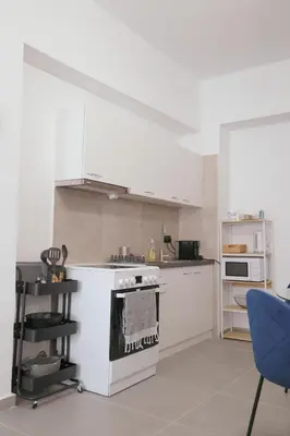 a white kitchen with a stove and a blue chair at Heart of Athens Stay #6 in Athens