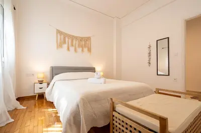 a white bedroom with two beds and a table at Miss H Haven in Athens