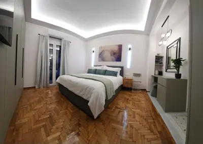 a bedroom with a large bed and a wooden floor at Sourmel Apt in Athens