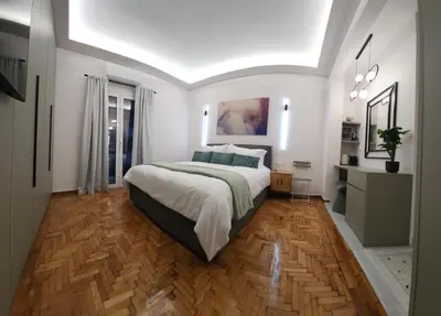 a bedroom with a large bed and a wooden floor at Sourmel Apt in Athens