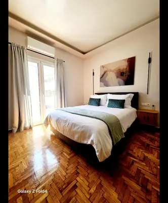 a bedroom with a large bed and a large window at Sourmel Apt in Athens
