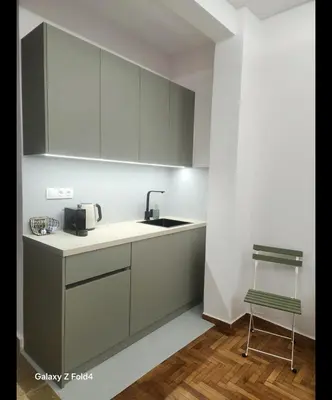 a kitchen with gray cabinets and a sink and a chair at Sourmel Apt in Athens