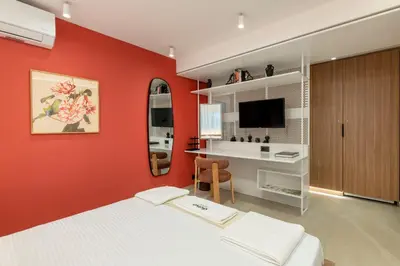 a bedroom with a red wall with a bed and a desk at Glyfada Coastside Apartment in Athens