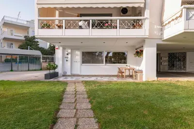 a white house with a balcony and a table at Glyfada Coastside Apartment in Athens