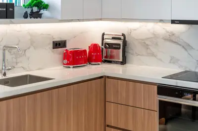 a kitchen with white marble counter tops and red toasters at Glyfada Coastside Apartment in Athens