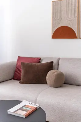 a couch with pillows and a book on a table at Modern Athenian Nest near Kallimarmaro Stadium by UPSTREET in Athens