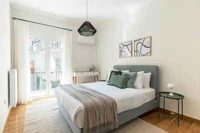 a bedroom with a bed and a large window at Modern Athenian Nest near Kallimarmaro Stadium by UPSTREET in Athens