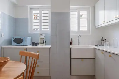 a white kitchen with a sink and a table at Casa Riviera-Newly Renov 2Br Luxury Apt near Sea in Athens