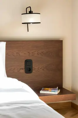 a bed with a wooden head board with a light above it at Immaculate Modern Kypseli Apt - Next to Kanari Sq in Athens