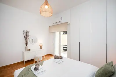 a white bedroom with a bed and a window at Kolonaki Prestige - Greecing in Athens