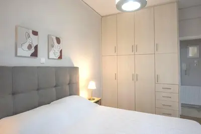 a bedroom with a large white bed and cabinets at Urban Comfort Stay in Athens