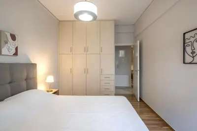 a bedroom with a large white bed and a closet at Urban Comfort Stay in Athens