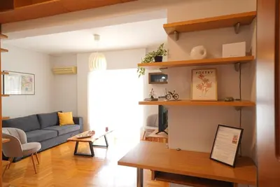 a living room with a blue couch and wooden shelves at Family Flat for 4 next to the Flisvos Marina by Filos Inc in Athens