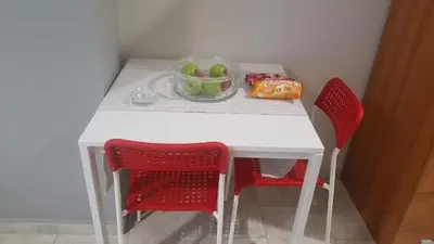 a white table with two red chairs and a bowl of fruit at Sunny apartment in the heart of Pireaus in Piraeus