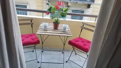 a table and two chairs with red cushions on a balcony at Sunny apartment in the heart of Pireaus in Piraeus
