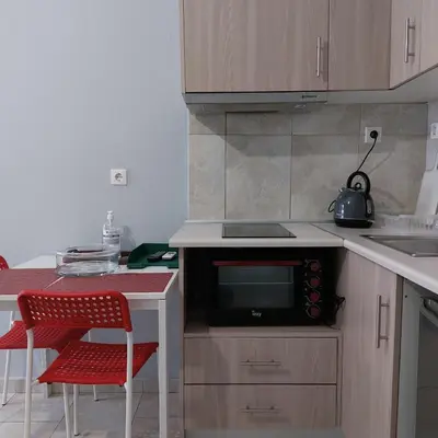 a kitchen with a microwave and a table with red chairs at Sunny apartment in the heart of Pireaus in Piraeus