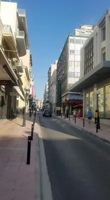a city street with buildings and a car on the road at Sunny apartment in the heart of Pireaus in Piraeus