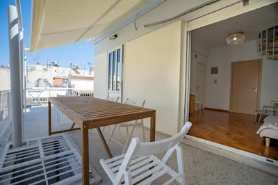 a wooden table and chairs in a room with a balcony at Breezy Maisonette in Zea for 5 by Filos Inc in Piraeus
