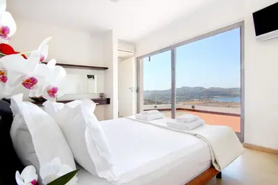 a bedroom with a white bed and a large window at Villa TakeOff Saronida in Anavissos