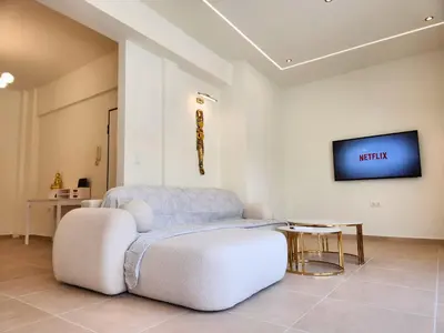 a living room with a white chair and a tv at Prestige in Athens