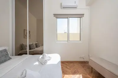 a white bedroom with a bed and a mirror at Lycabettus View Top Floor 2BdApt in Athens