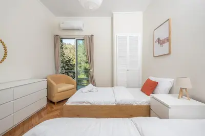 a white bedroom with two beds and a chair at Lycabettus View Top Floor 2BdApt in Athens