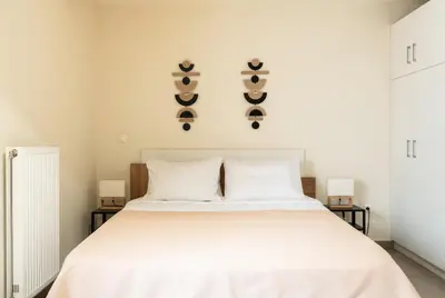 a bedroom with a large white bed with two pillows and two lights at Elysee apartment 2 in Athens