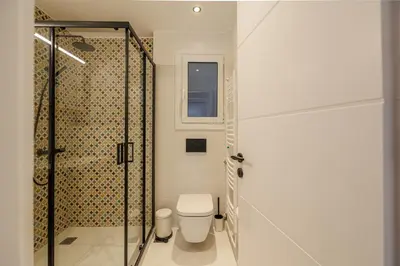 a bathroom with a toilet and a glass shower at Cozy 3 bdr Apartment next to Acropolis in Athens