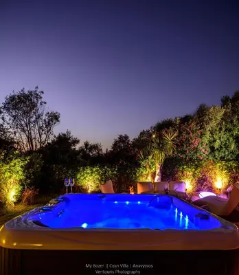 a swimming pool in a yard at night with lights at Cyan Villa in Anavissos