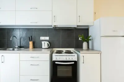 a kitchen with white cabinets and a black oven at Elysee apartment 3 in Athens