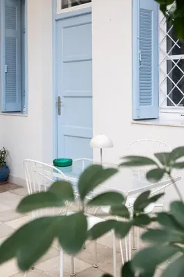 a glass table with two chairs and a blue door at Athenian Cypress House in Athens