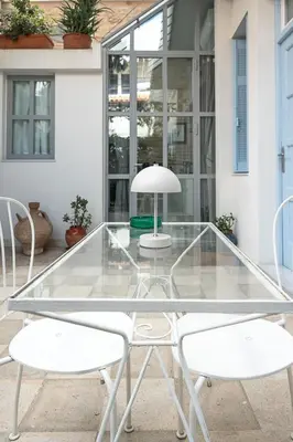 a glass table with two white chairs and a lamp at Athenian Cypress House in Athens