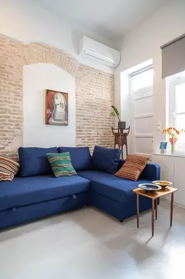 a blue couch in a living room with a brick wall at Athenian Cypress House in Athens