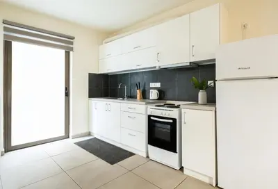 a white kitchen with white cabinets and a refrigerator at Elysee apartment 5 in Athens