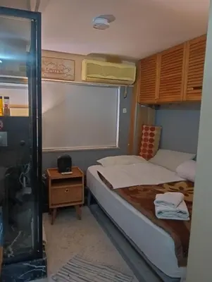 a small bedroom with a bed and a night stand at OneStep mini apartment next to Kallimarmaro Stadium in Athens