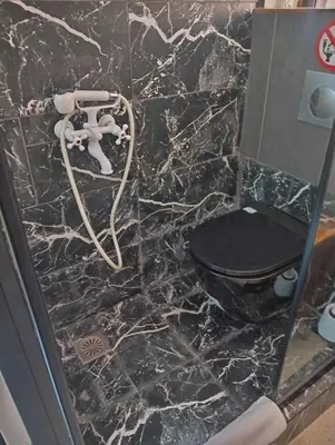 a bathroom with a black toilet and a marble floor at OneStep mini apartment next to Kallimarmaro Stadium in Athens
