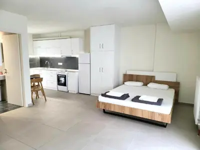 a large white bedroom with a bed and a kitchen at Elysee apartment 7 in Athens