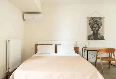 a bedroom with a bed with a desk and a painting at Elysee apartment 8 in Athens