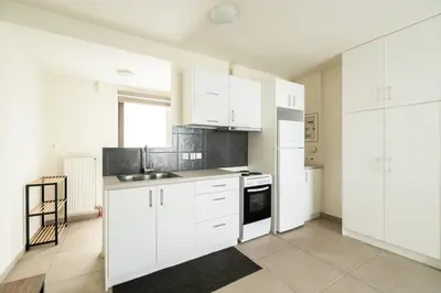 a white kitchen with white cabinets and a sink at Elysee apartment 8 in Athens
